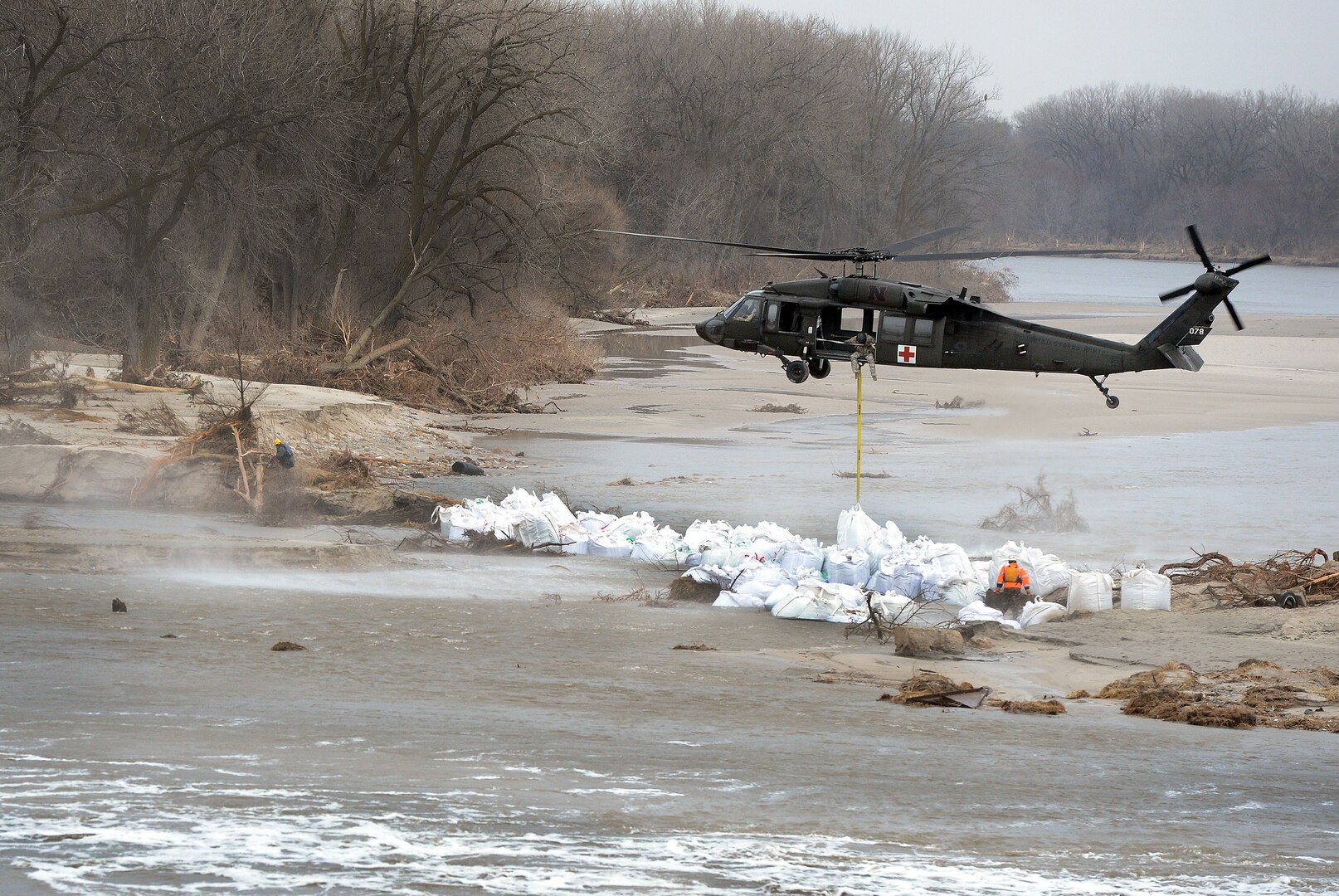 An aircrew with the Nebraska Army National Guard's 2nd Battalion, 104th Aviation Regiment, uses a UH-60 Black Hawk helicopter to lower 1,500-pound sandbags into place to stem flooding from a breached levee along the Loup River, Nebraska. More than 340 Guard members have responded to flooding in Nebraska, Missouri, Iowa and other Midwest states.