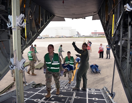 Air Force Maj. Carolyn Stateczny (right), 433rd Aeromedical Evacuation Squadron flight nurse, guides Spcs. Sandessa Jones and Maryssa Alfonso, Brooke Army Medical Center, into a C-130H Hercules aircraft to load a simulated litter patient for air transport at Joint Base San Antonio-Lackland March 20. Several military and civilian organizations participated in a National Disaster Medical System exercise