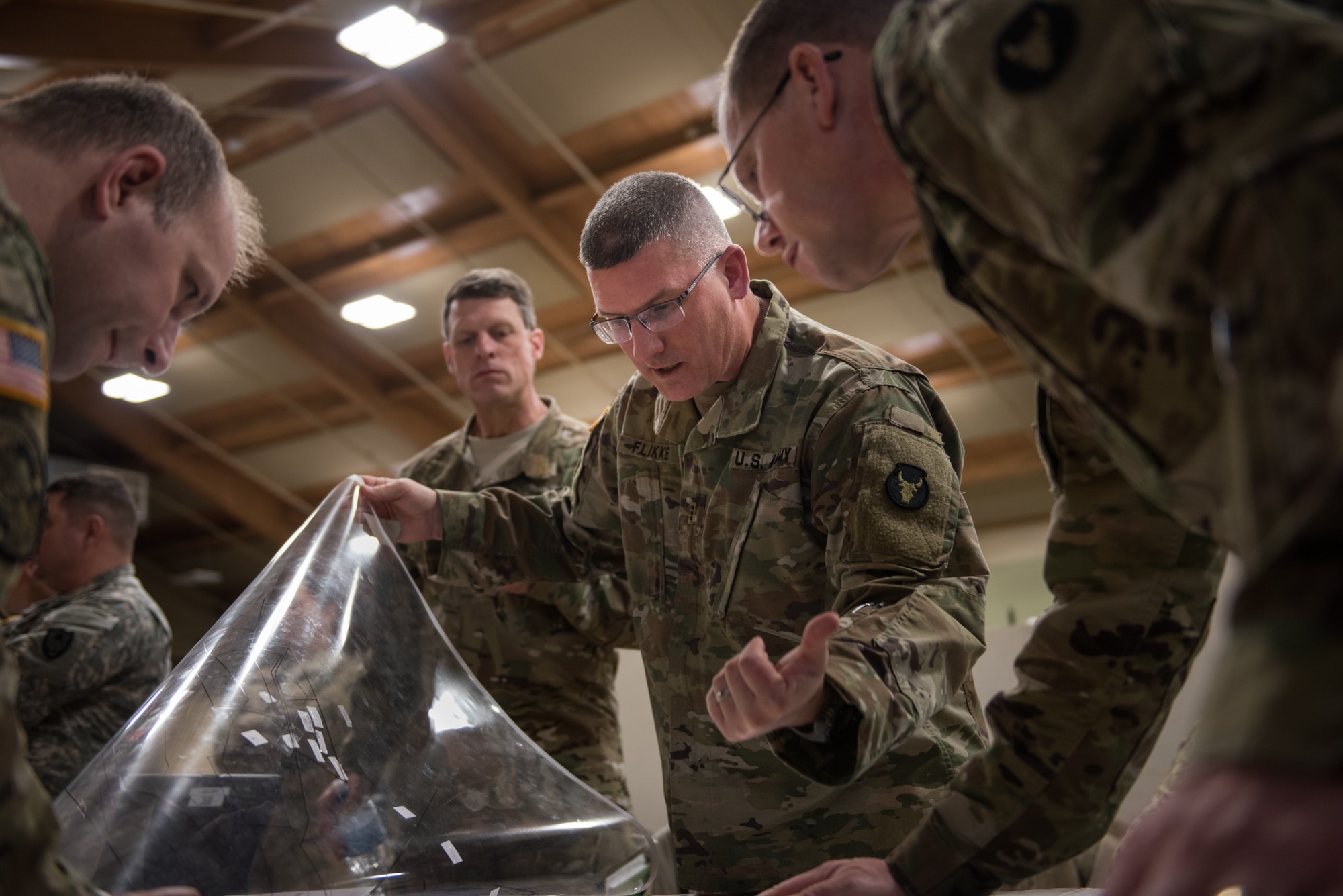 Chief Warrant Officer 3 Jonathan Flikke, brigade targeting officer for the Minnesota Army National Guard Armored Brigade Combat Team, 34th Infantry Division (1/34th ABCT), lifts a clear cover to a map during a discussion of troop positions in a simulated attack during the 19-05 Command Post Exercise (CPX) for the 1/34th ABCT, March 8-9, 2019, at Camp Ripley in Little Falls, Minn. The CPX was a practice virtual battle exercise for the brigade to practice their battle drills, and the 146th ASOS will continue partnering with the 1/34th ABCT later in the year to assist in a graded warfighter exercise, as well as other trainings next year. (U.S. Air National Guard photo by Staff Sgt. Brigette Waltermire)