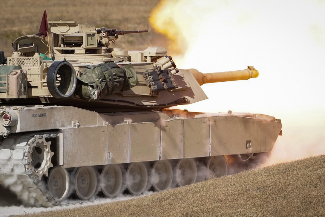 Flames emerge from a tank’s main gun during a daylight range.