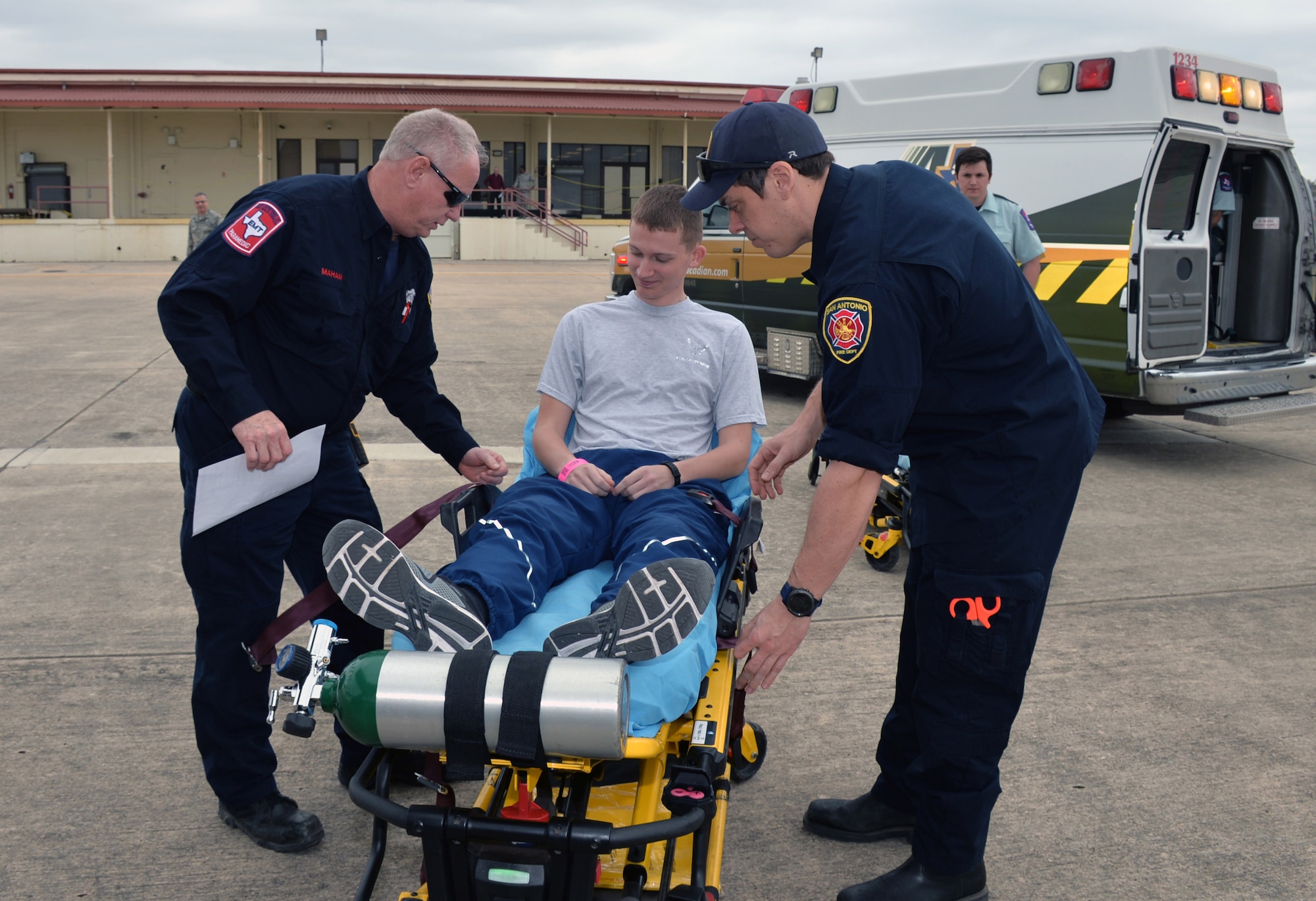 San Antonio paramedic firefighters, Richard Mahan and Dave McCulley, secure seatbelts on Airman Davis Schleifer, 344th Training Squadron, during a National Disaster Medical System exercise March 20, 2019 at Joint Base San Antonio-Lackland, Texas.