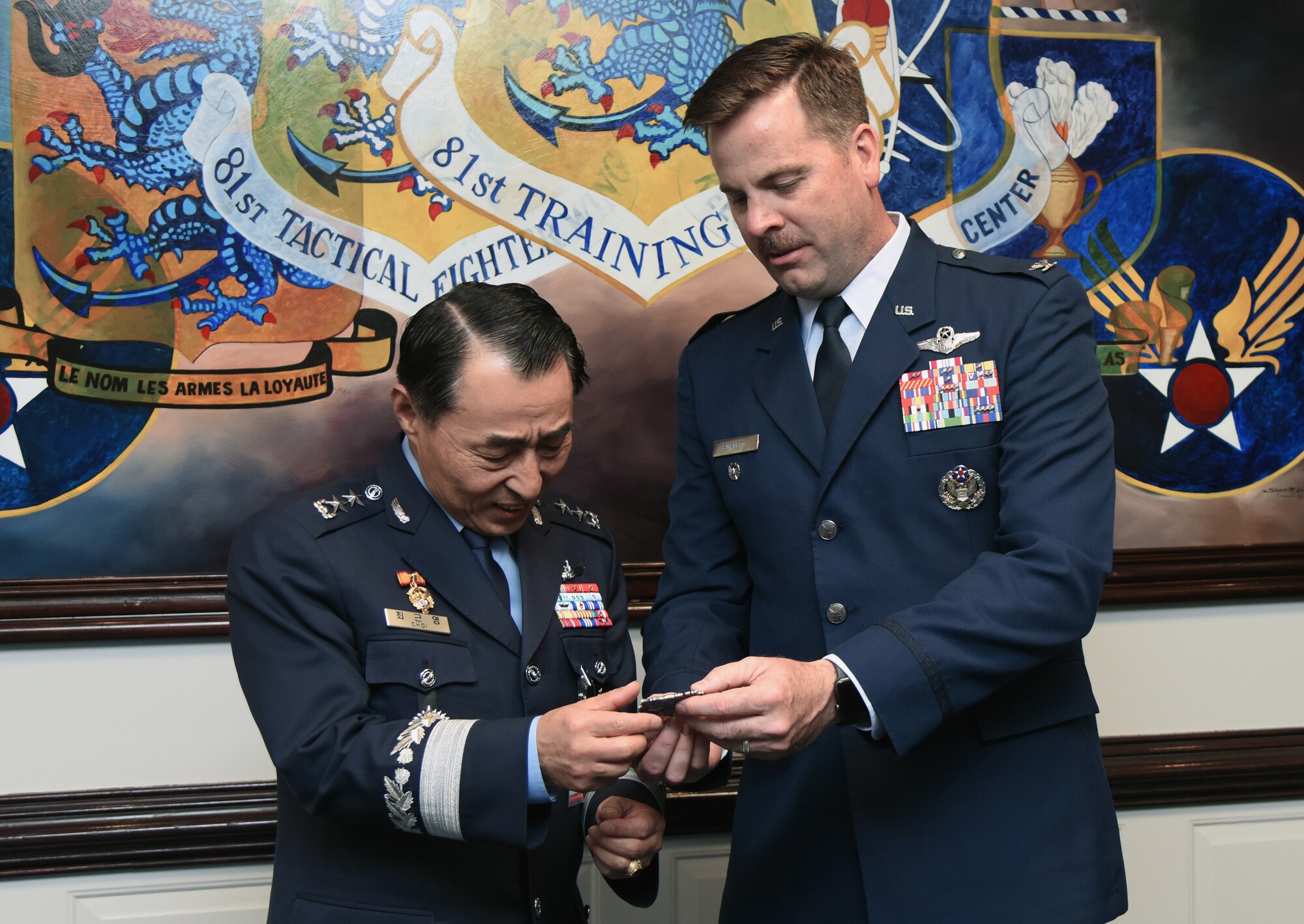 U.S. Air Force Col. Lance Burnett, 81st Training Wing vice commander, presents a coin to Republic of Korea Air Force Maj. Gen. Geunyoung Choi, ROKAF Air Education and Training Command commander, following an 81st TRW mission brief at the headquarters building on Keesler Air Force Base, Mississippi, March 22, 2019. Choi visited Keesler to help better develop ROKAF technical education through visiting U.S. Air Force future technology education sites.  (U.S. Air Force photo by Kemberly Groue)