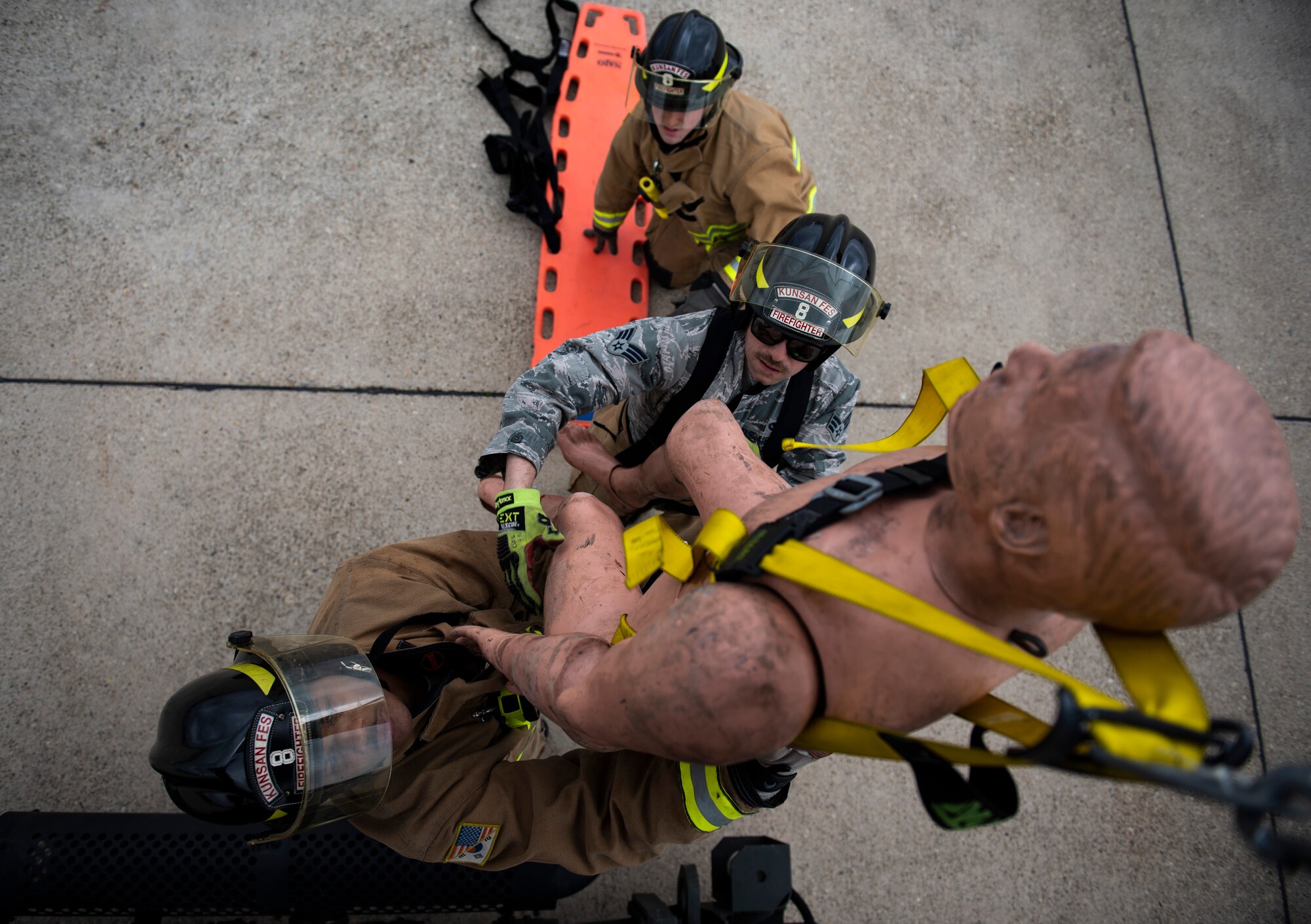 Fire fighters from the 8th Civil Engineer Squadron rescue a mannequin simulating a fall victim at Kunsan Air Base, Republic of Korea, March 26, 2019. This was the first time the fire department exercised retrieving someone hanging in a harness from an aircraft cargo loader. (U.S. Air Force phot by Senior Airman Stefan Alvarez)