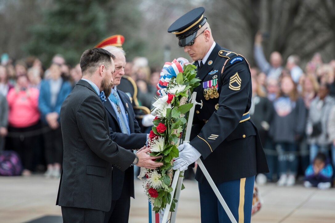 A group of men place a wreath  during a ceremony at Arlington National Cemetery.