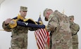 Col. Michael J. Simmering, left, and Command Sgt. Maj. Samuel C. Rapp, right, unfurl the 3rd Armored Brigade Combat Team, 4th Infantry Division colors during a transfer of authority ceremony at Camp Buehring, Kuwait, on March 23, 2019. As commander of the 3ABCT, Simmering assumed authority for the ongoing brigade combat team mission within Task Force Spartan, in support of Operation Spartan Shield.