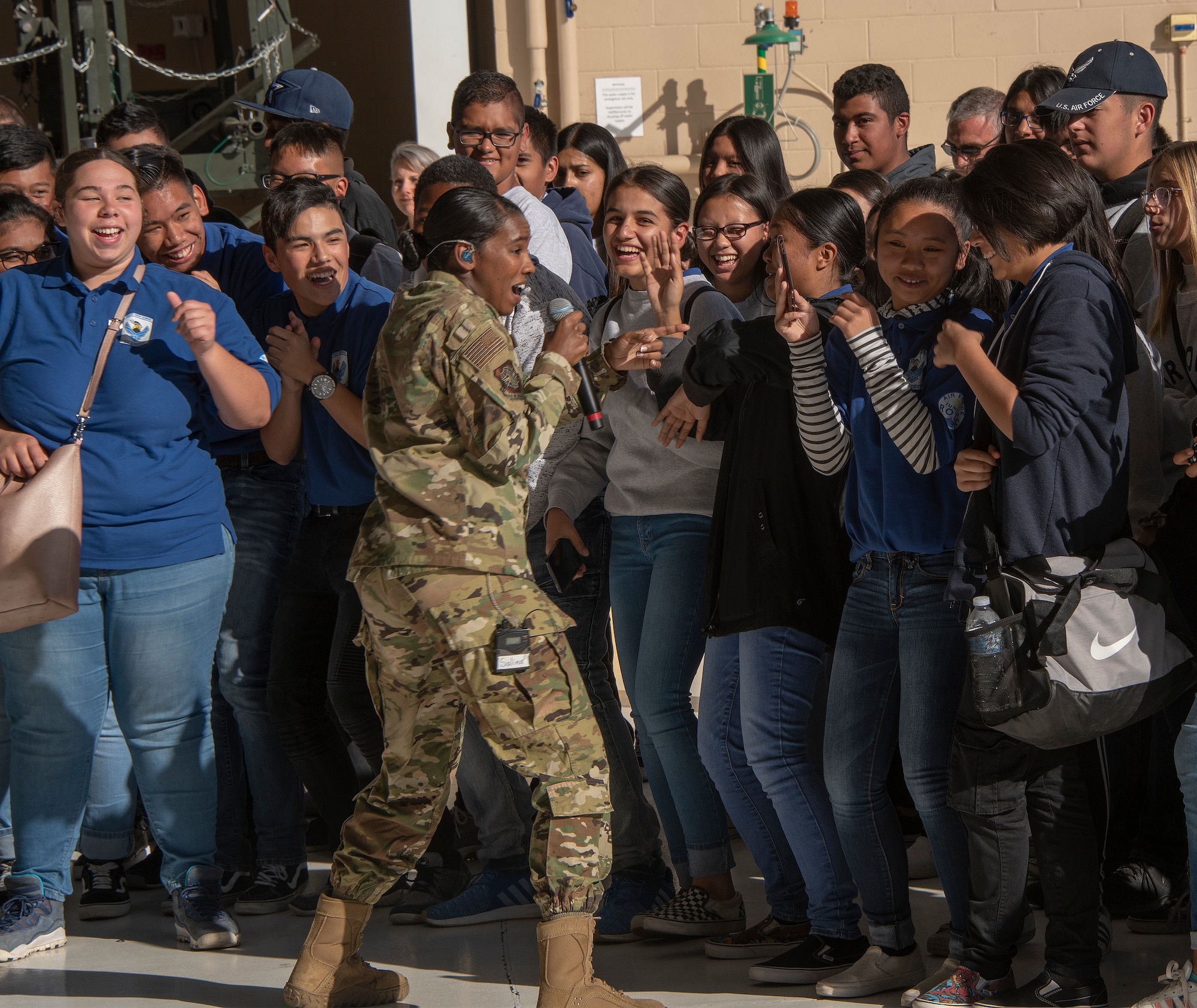 U.S. Air Force Senior Airman Salina Boodoosingh, a vocalist with the United States Air Force Band of the Golden West, gets the crowd moving, Nov. 8, 2018, Travis Air Force Base, California. Travis hosted Junior Reserve Officer Training Corps students from three high schools in Northern Calif. Students learned about various career fields in the U.S. Air Force, toured static aircraft, a dormitory, and had the opportunity to talk with personnel about military life. (U.S. Air Force photo by Heide Couch)