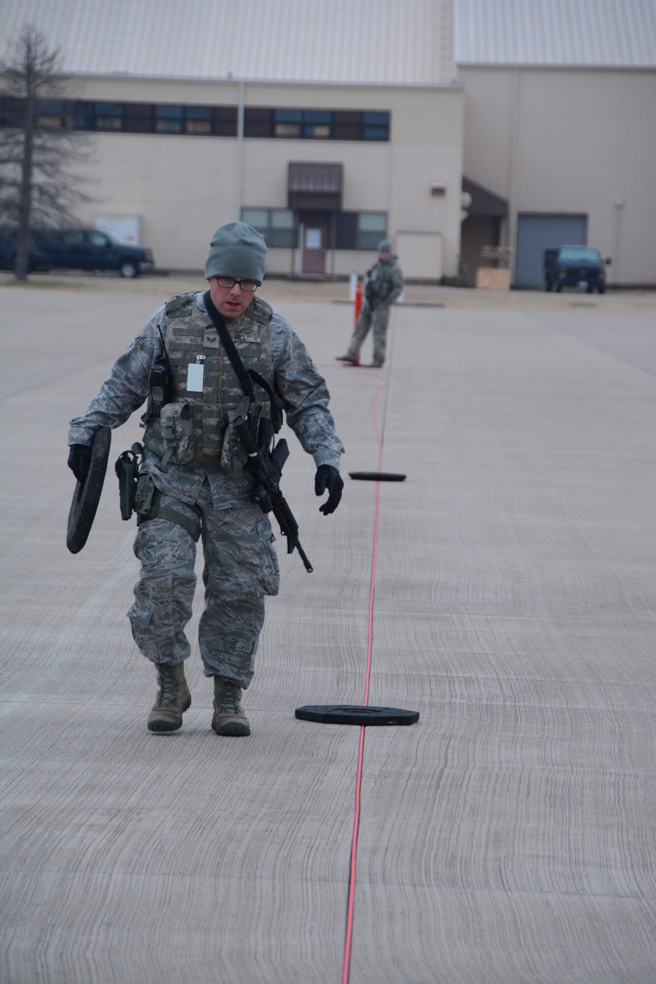 Senior Airman Steven Hill, 507th Security Forces Squadron, places stanchion bases along a perimeter of rope securing aircraft on the flightline during an exercise geared toward wartime preparation and readiness March 2, 2019, at Tinker Air Force Base, Oklahoma. The 507th Air Refueling Wing's unit effectiveness inspection capstone event is scheduled for Nov. 15-19, 2019. (U.S. Air Force photo by Tech. Sgt. Lauren Gleason) (This photo has been altered for security purposes by blurring out identification badges.)