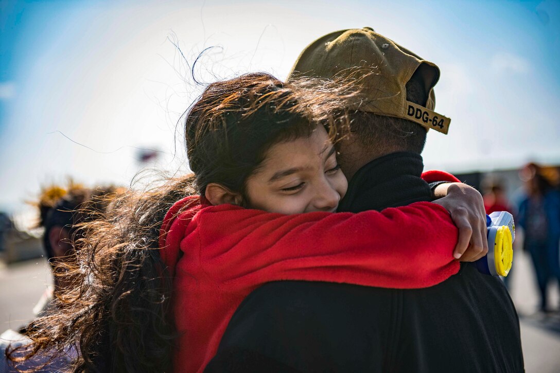 A young girl hugs her father.