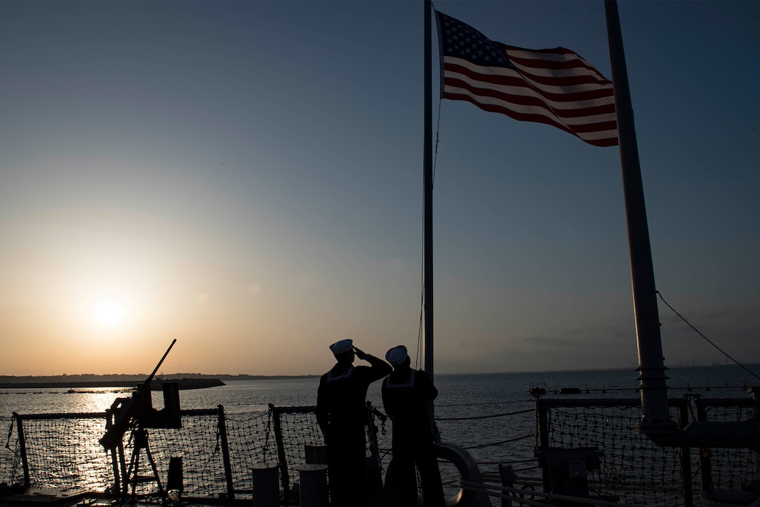 Service members raise the American flag.