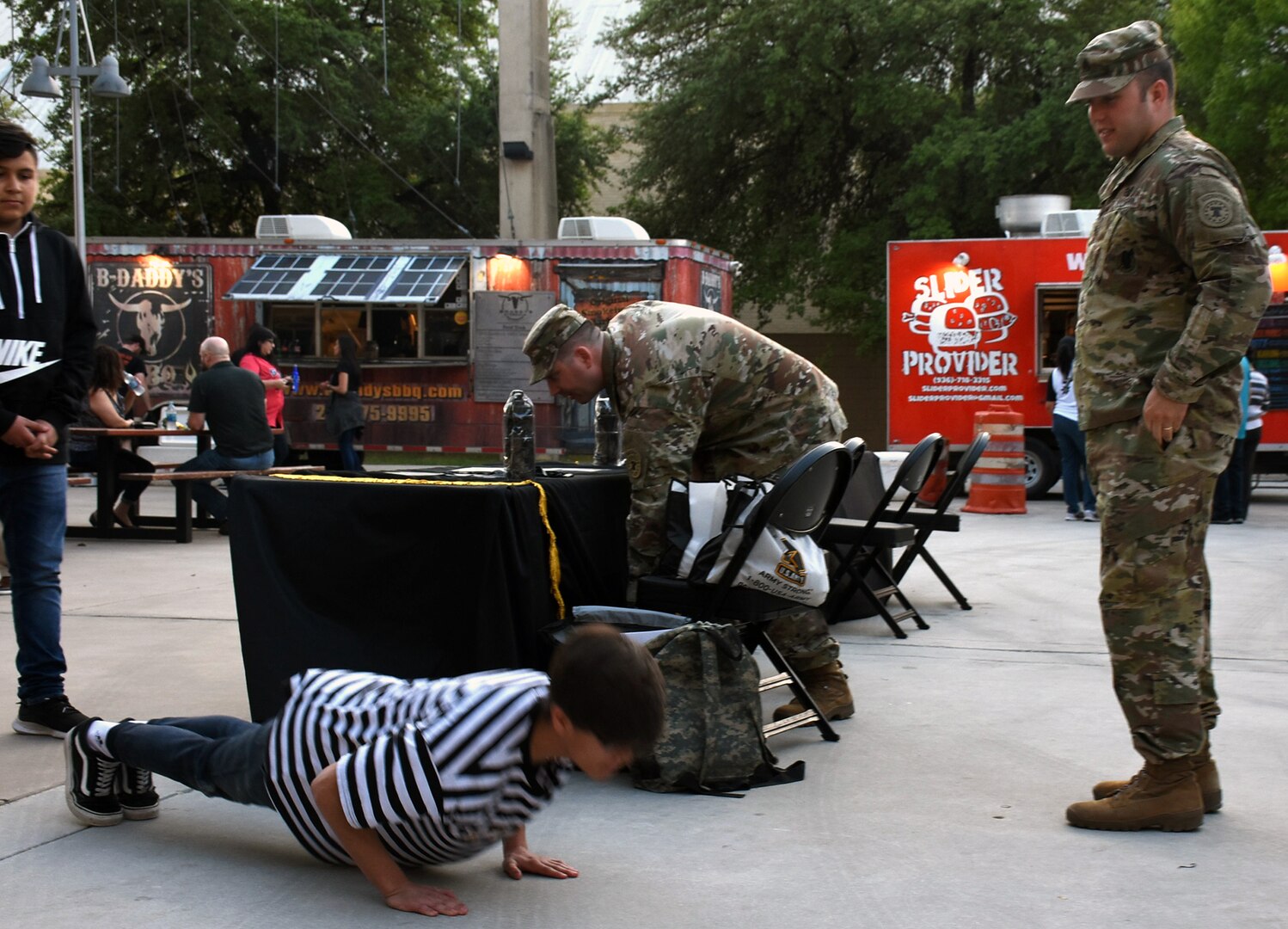 Staff Sgt. Jarred Dunton, recruiter with Company E, San Antonio Recruiting Battalion, counts the pushups done by a teenager at the Spurs Military Appreciation Night March 20 at the AT&T Center.