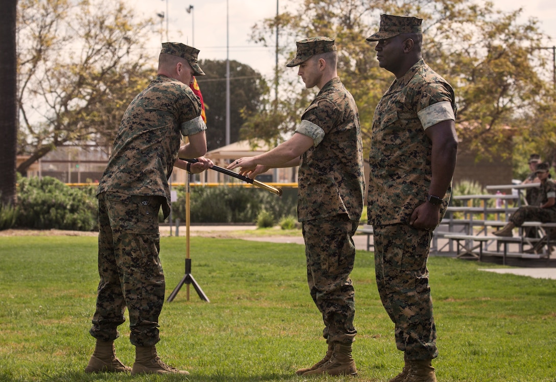 Lt. Col. Alan J. Clarke, commanding officer of Headquarters and Headquarters Squadron (H&HS), passes the sword of office to Sgt. Maj. John K. Lewis, the oncoming sergeant major for H&HS, during a relief and appointment ceremony on Marine Corps Air Station Miramar, Calif., Mar. 22. The ceremony formally recognized Sgt. Maj. Broadus for his honorable service and welcomed Lewis as the new squadron sergeant major. (U.S. Marine Corps photo by Cpl. Becky Cleveland)
