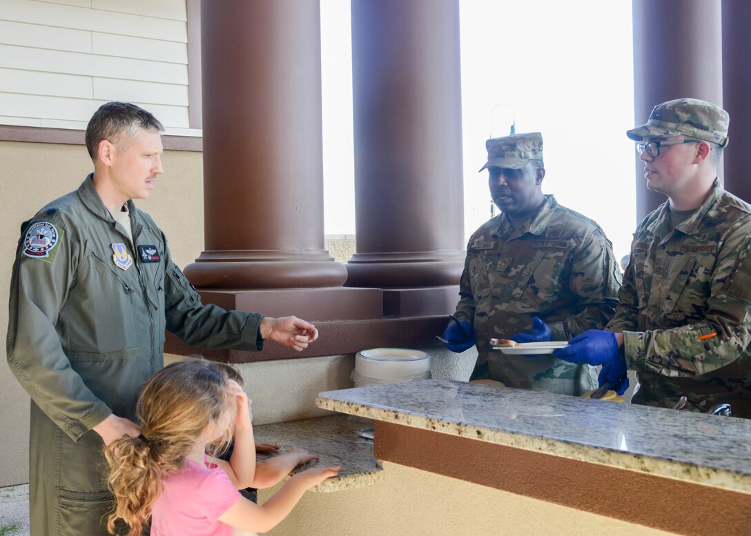 Chief Master Sgt. James Coleman, 412th Test Wing acting command chief, and Airman 1st Class Cameron Hawthorne, 412th Aerospace Medicine Squadron, serve food to Lt. Col. Tucker Hamilton, 461st Flight Test Squadron commander, and his children during a Strong Family Program event at the Mojave Sky Community Center at Edwards Air Force Base, California, March 18. (U.S. Air Force photo by Giancarlo Casem)
