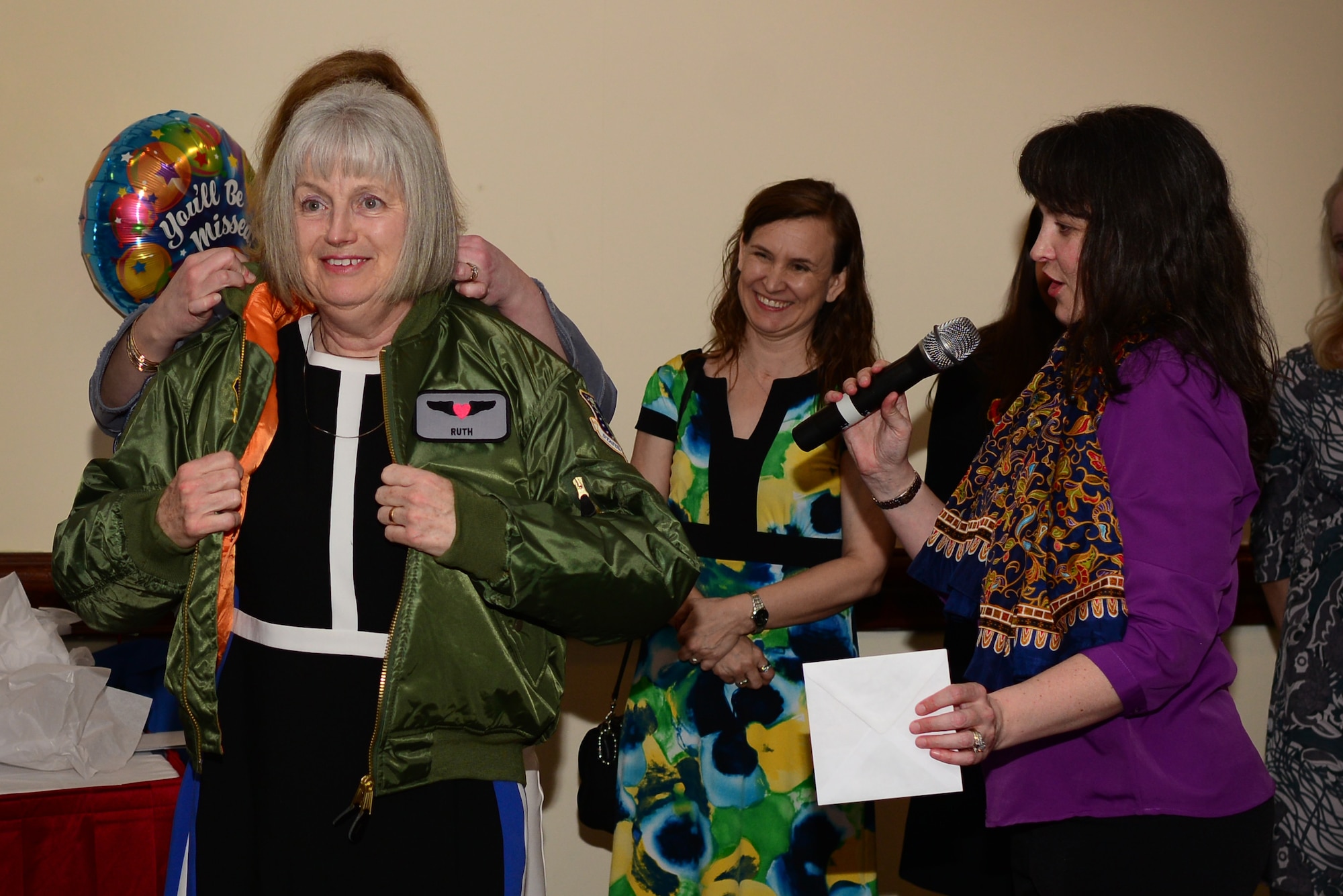 Ruth Neild is presented with a custom aviator jacket by members of the 48th Fighter Wing key spouses during a farewell event at Royal Air Force Lakenheath, England, March 26, 2019. Neild and her newly retired husband Jerry received numerous tokens of appreciation for their 12 years of service at RAF Lakenheath. (U.S. Air Force photo/ Tech. Sgt. Matthew Plew)