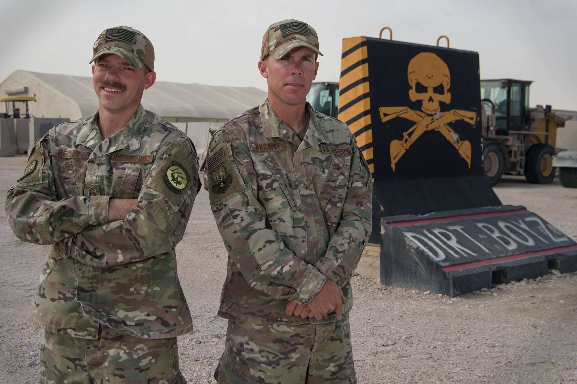 Master Sgt. Christopher Beckett, left, 379th Expeditionary Civil Engineer Squadron (ECES) heavy equipment section chief, and Tech. Sgt. John Beckett, 379th ECES heavy equipment project lead, stand together in front of the 379th ECES “Dirt Boyz” barrier March 27, 2019, at Al Udeid Air Base, Qatar. The brothers, who have served in the Arizona Air National Guard since 2003, are currently deployed together to the same ECES unit at Al Udeid Air Base. (U.S. Air Force photo by Tech. Sgt. Christopher Hubenthal)