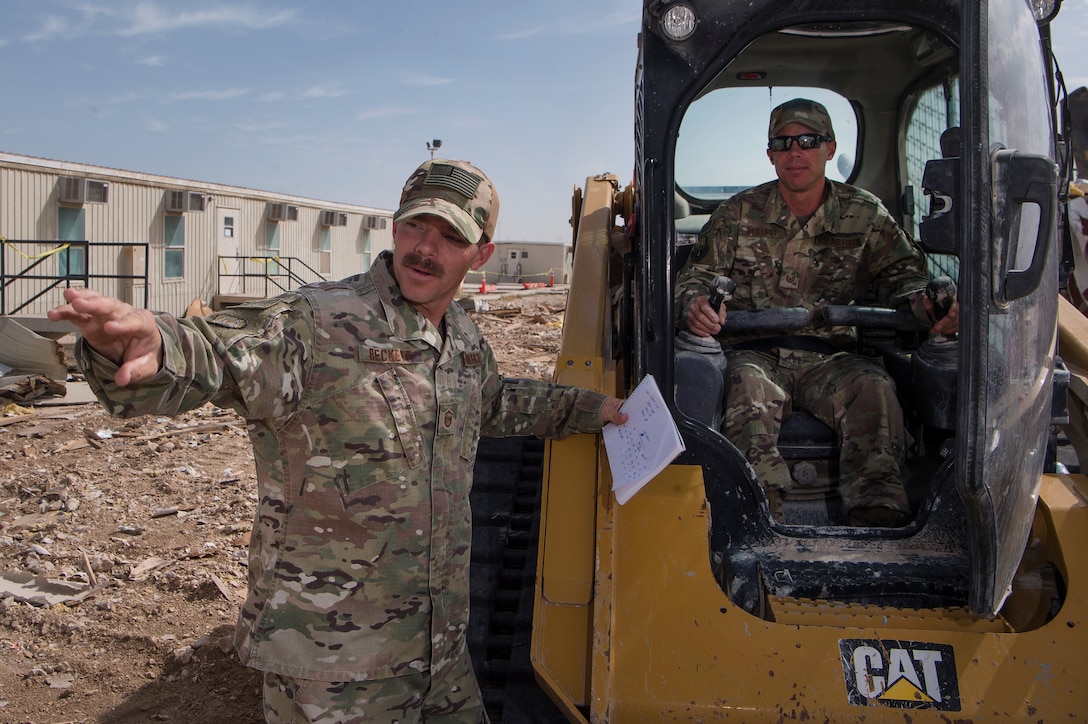 Master Sgt. Christopher Beckett, left, 379th Expeditionary Civil Engineer Squadron (ECES) heavy equipment section chief, and Tech. Sgt. John Beckett, right, 379th ECES heavy equipment project lead, work together at a construction site March 27, 2019, at Al Udeid Air Base, Qatar. The brothers, who have served in the Arizona Air National Guard since 2003, are currently deployed together to the same ECES unit at Al Udeid Air Base. (U.S. Air Force photo by Tech. Sgt. Christopher Hubenthal)
