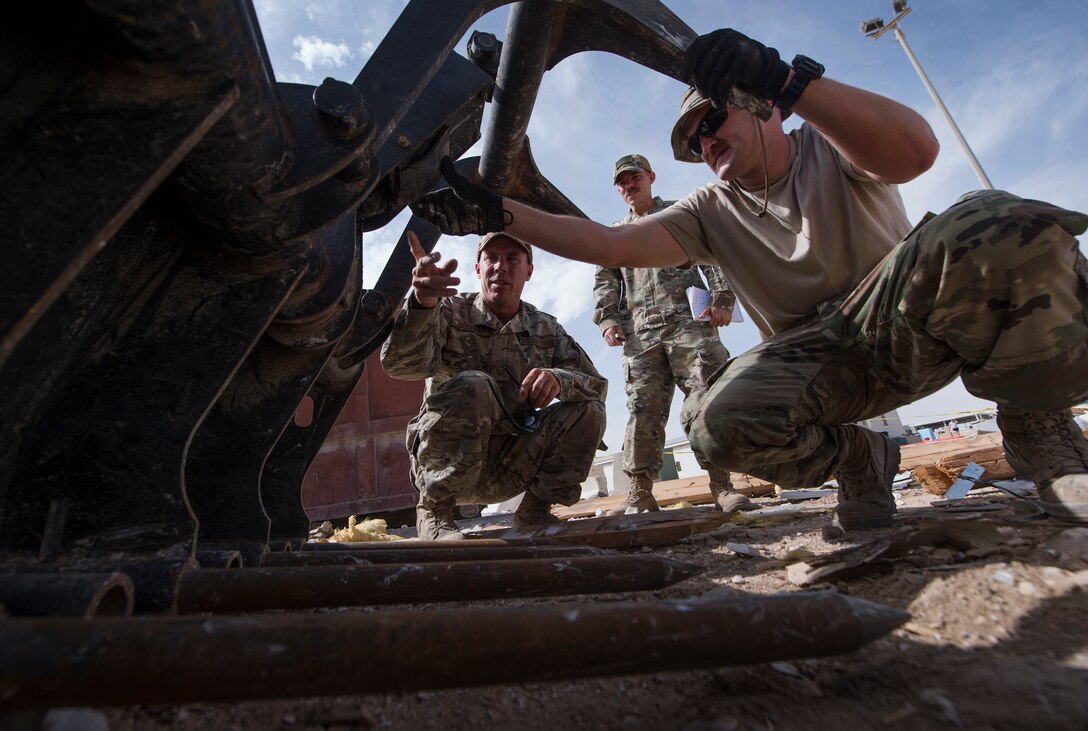 Tech. Sgt. John Beckett, left, 379th Expeditionary Civil Engineer Squadron (ECES) heavy equipment project lead, Master Sgt. Christopher Beckett, 379th ECES heavy equipment section chief, and Staff Sgt. Justin Emanuelson, right, 379th ECES pavement and equipment operator, troubleshoot a construction vehicle March 27, 2019, at Al Udeid Air Base, Qatar. The brothers, who have served in the Arizona Air National Guard since 2003, are currently deployed together to the same ECES unit at Al Udeid Air Base. (U.S. Air Force photo by Tech. Sgt. Christopher Hubenthal)
