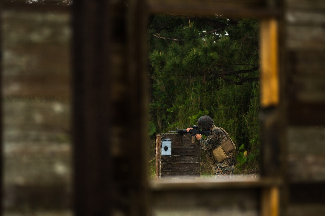 A service member aims a gun.