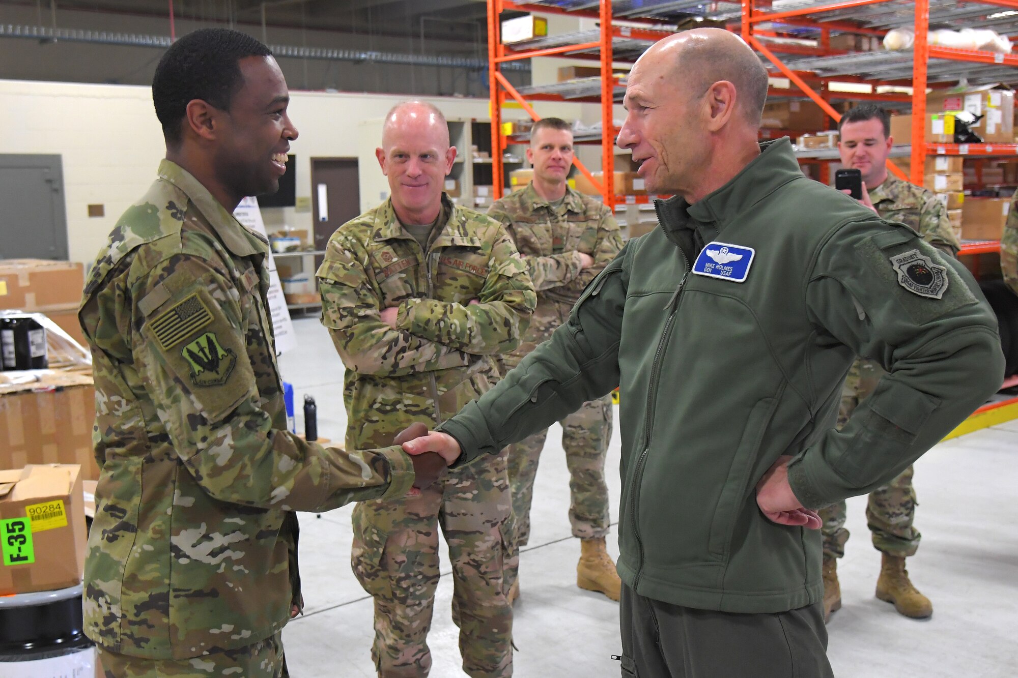 U.S. Air Force Senior Airman Joshua Inman, 388th Maintenance Group scheduler, is coined for outstanding performance by U.S. Air Force Gen. Mike Holmes, commander of Air Combat Command, as ACC Command Chief Master Sgt. Frank Batten, center, looks on during a visit to the 388th Fighter Wing March 26, 2019, at Hill Air Force Base, Utah. (U.S. Air Force photo by Todd Cromar)