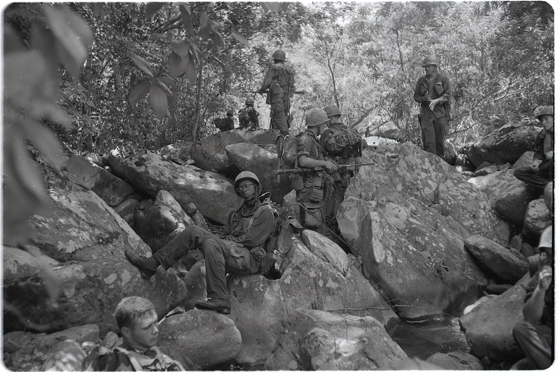 Marines relax on rocks in the Vietnamese jungle.