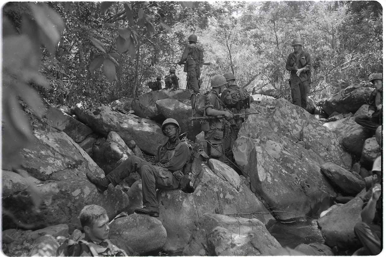 Marines relax on rocks in the Vietnamese jungle.