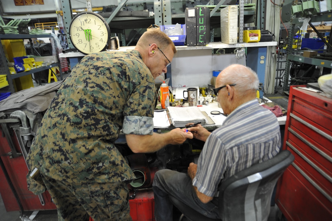 Telfinues Preszler, a heavy equipment mechanic better know as Pap Tel, receives a commander's coin from Brigadier General Joseph Schrader, Commanding General, Marine Corps Logistics Command, during a tour of Production Plant Barstow, Marine Depot Maintenance Command, on the Yermo Annex, aboard Marine Corps Logistics Base Barstow, Calif., July 17, 2018.