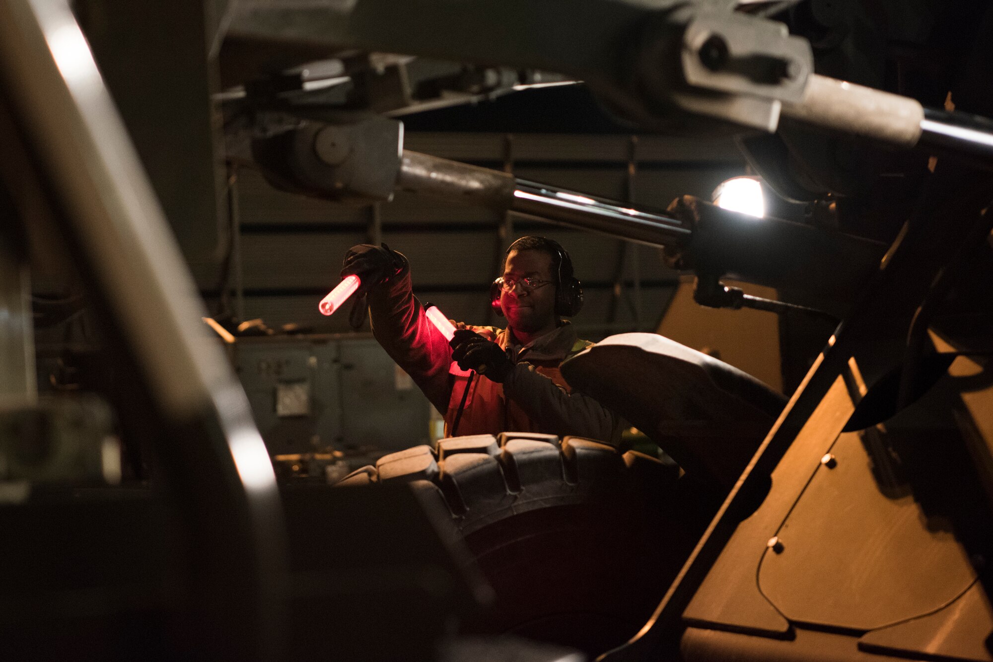 Airman 1st Class Juwan White, 732d Air Mobility Squadron aircraft services technician, uses lights to signal a 10K all-terrain forklift to unload a pallet onto a 60k loader during Polar Force 19-4 at Joint Base Elmendorf-Richardson, Alaska, March 25, 2019. Polar Force is a two-week exercise designed to test JBER’s mission readiness. Exercises like this strengthen and develop the skills service members require when facing adverse situations.