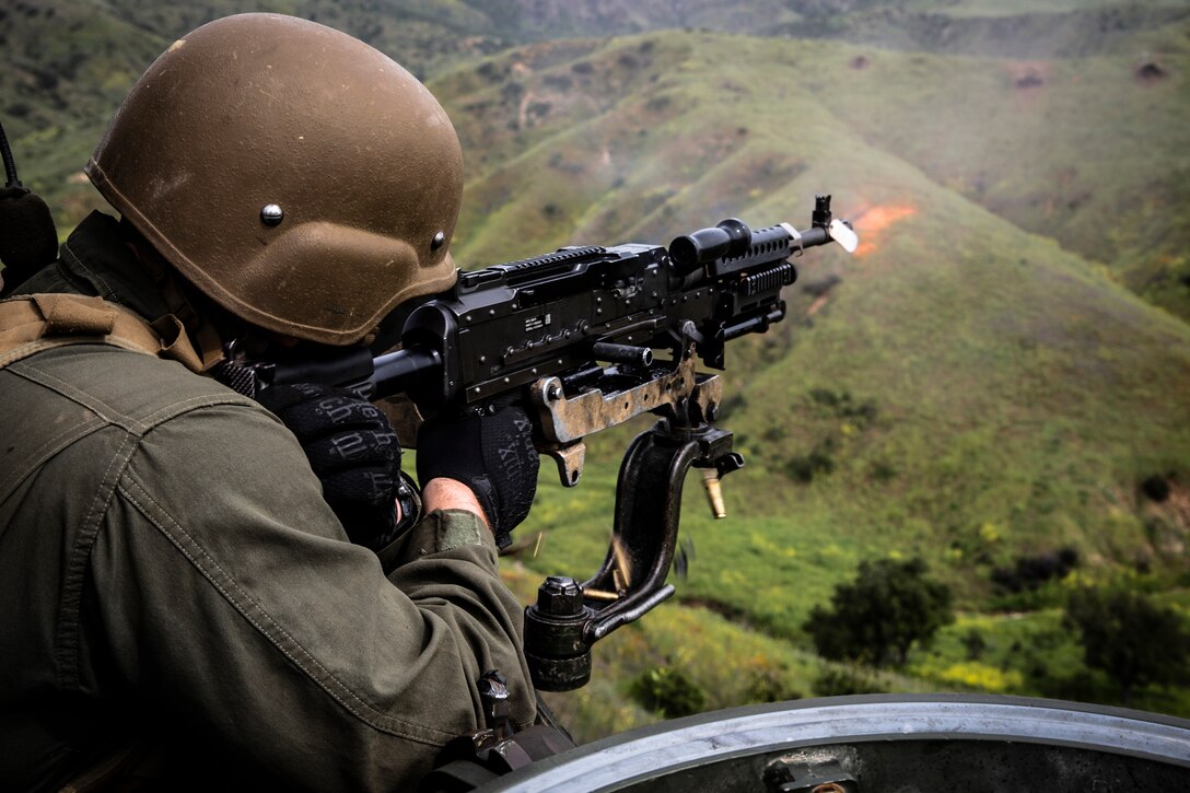 A Marine fires a machine gun from the air.