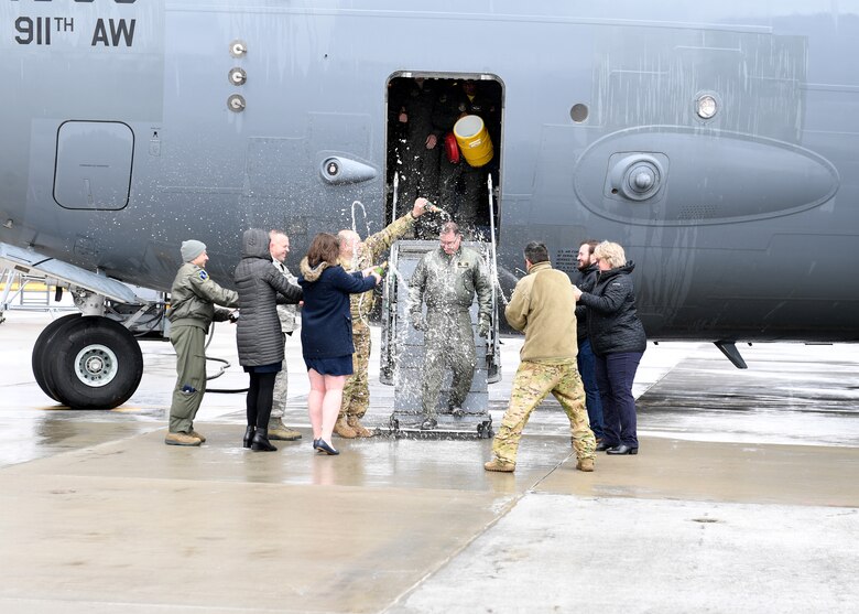 Lt. Col. Bryan Branby, chief of the 911th Airlift Wing Program Integration Office, gets sprayed champagne and water by family and friends after his last flight at the Pittsburgh International Airport Air Reserve Station, Pennsylvania, March 22, 2019. This is a tradition when an aircrew member walks off the aircraft after the final flight of their military career to celebrate their years of flying with the U.S. Air Force. (U.S. Air Force photo by Senior Airman Grace Thomson)