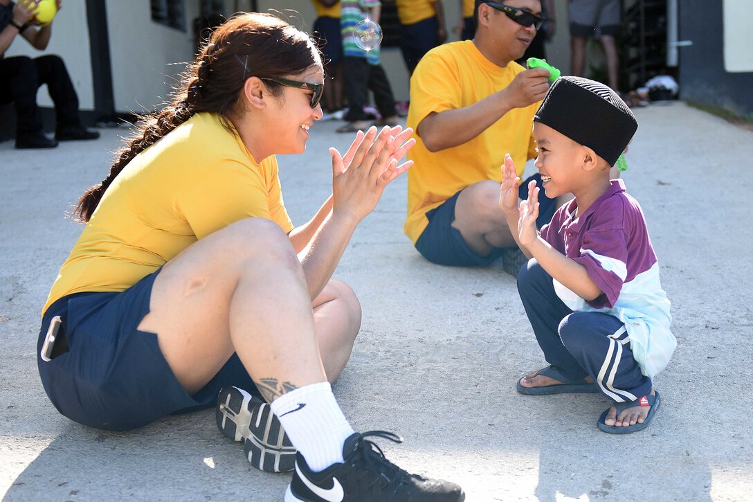 A service member and a child play a game.