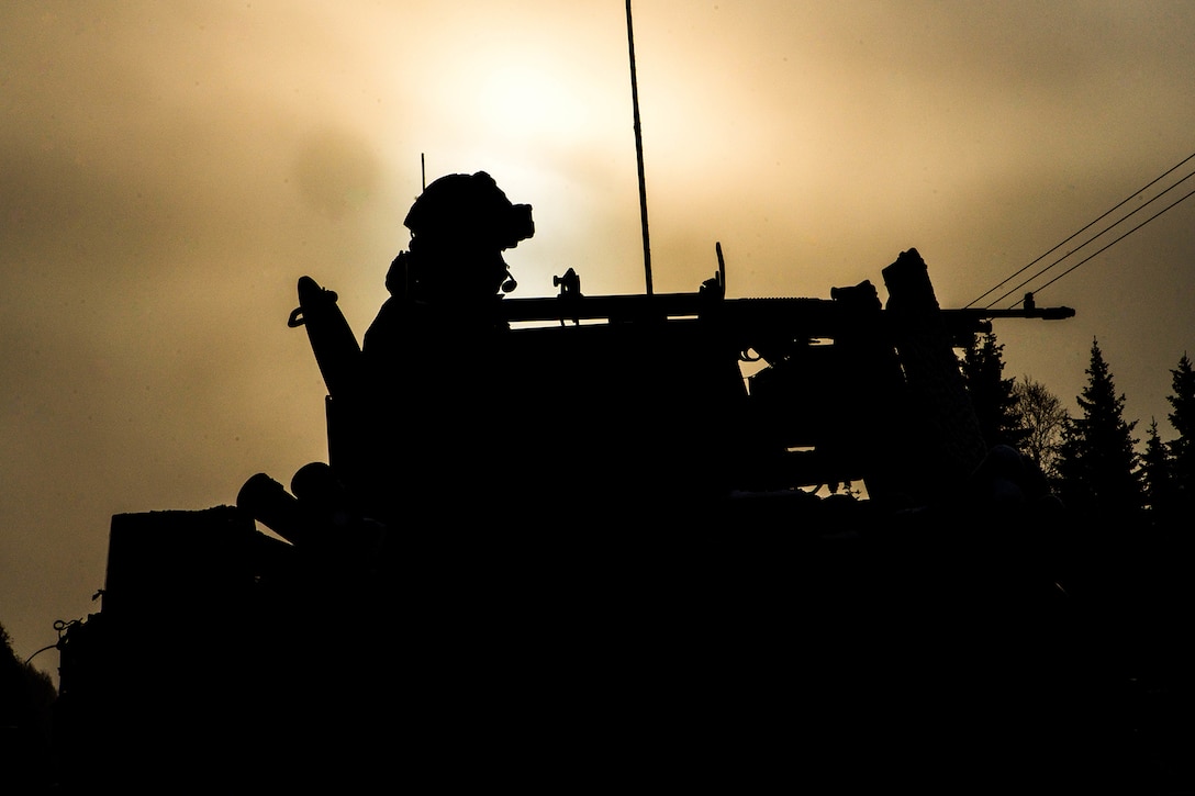 A service member fires a mounted weapon on a vehicle.