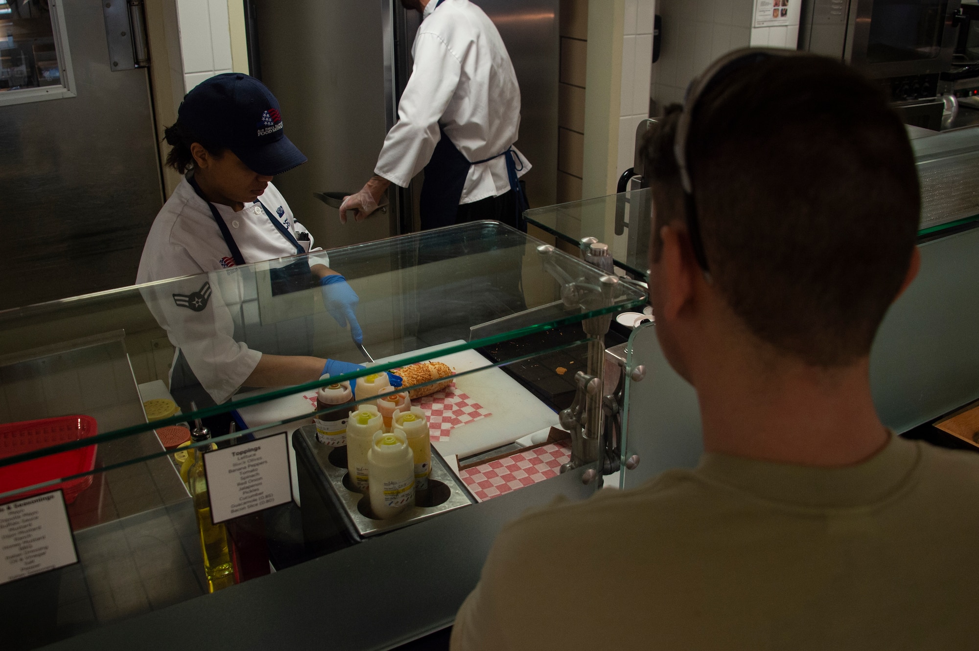 U.S. Air Force Airman 1st Class Reynesha Cecil, a food services member assigned to the 97th Force Support Squadron, cuts a sandwich for a customer, March 26, 2019, at Altus Air Force Base, Okla. The sandwich line is one of the daily options available to customers of Hangar 97. (U.S. Air Force photo by Senior Airman Cody Dowell)