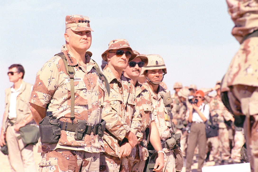 General and unit staff wearing desert camouflage inspect troops.