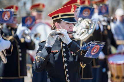 An Army musician plays a flute during a ceremony.