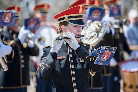 An Army musician plays a flute during a ceremony.