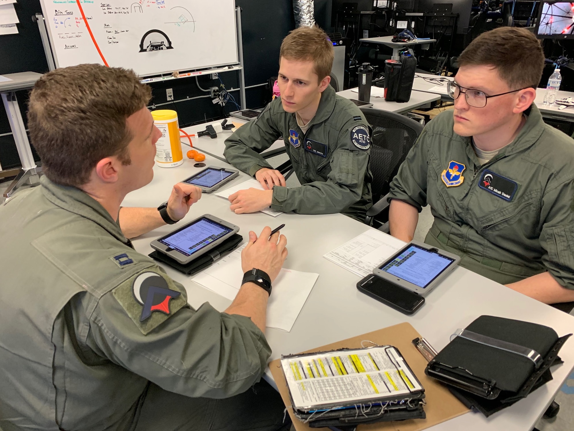 U.S. Air Force Capt. Jonathan Leetch, Pilot Training Next instructor pilot, debriefs students Royal Air Force Flight Officer Syd Janota (center), and Airman 1st Class Micah Daniel, after a virtual-reality training sortie at the PTN facility at the Armed Forces Reserve Center in Austin, Texas, March 18, 2019. The RAF is participating in PTN's second iteration in an effort to accelerate learning and increase pilot production. (U.S. Air Force photo/Dan Hawkins)