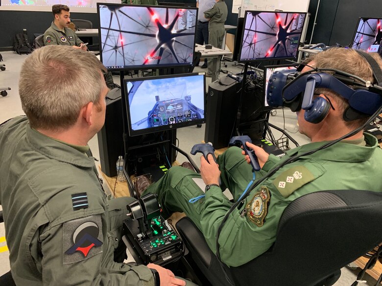 Royal Air Force Flight Lt. Darren French (left), Pilot Training Next 2.0 instructor pilot and the RAF's senior national representative, briefs British Army Col. Paddy Logan (center), assistant director for flying training for RAF Headquarters 22 Group, on technology lessons learned at the PTN facility at the Armed Forces Reserve Center in Austin, Texas, March 18, 2019. The RAF is participating in PTN's second iteration in an effort to accelerate learning and increase pilot production. (U.S. Air Force photo/Dan Hawkins)