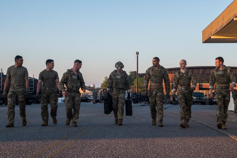 Airman 1st Class Aaron Griffith, 628th Logistics Readiness Squadron fuels distribution operator, middle, carries fuel supplies while his wingmen cheer him on during a forward area refueling point team tryout March 26, 2019, at Joint Base Charleston, S.C.