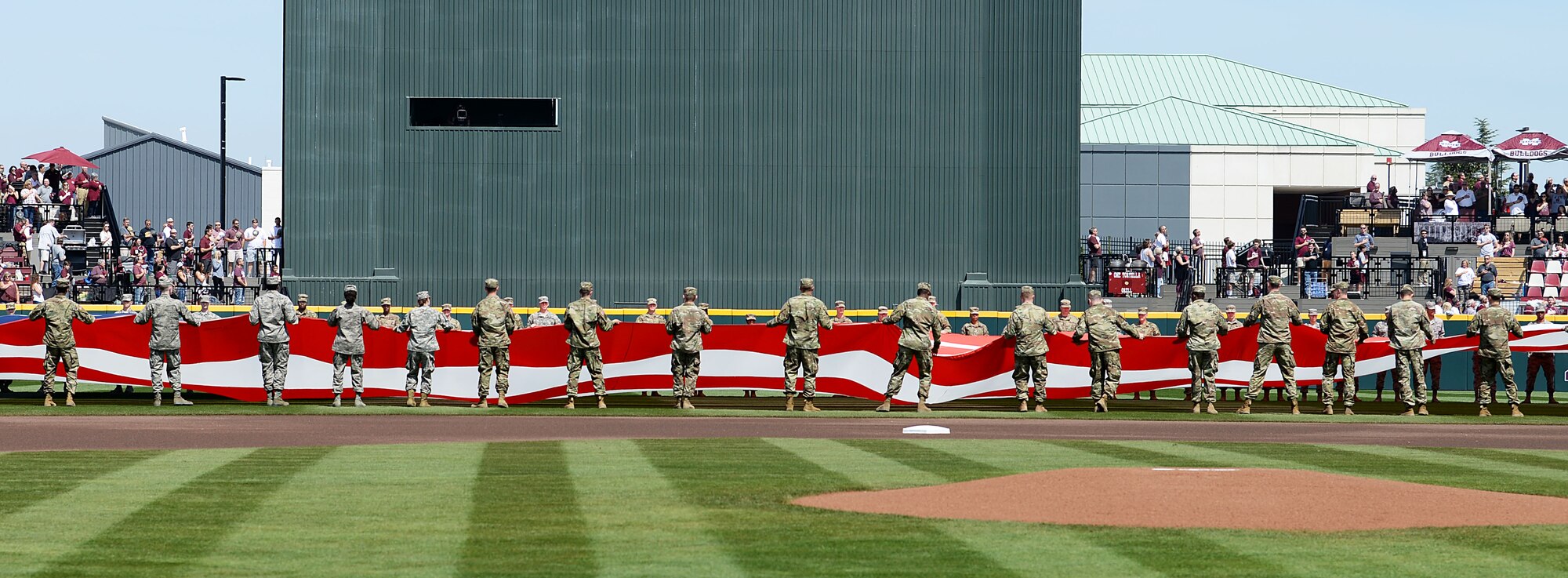 Military members unfurl the American Flag in the Dudy Noble Field at Mississippi State University March 23, 2019, in Starkville, Mississippi. MSU gave recognition to military members with a special “Salute to Service” performance before the game. (U.S. Air Force photo by Airman Hannah Bean)