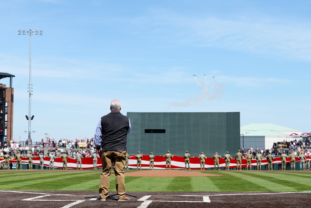 Military personnel present the flag during the singing of the national anthem at a military appreciation baseball game at Mississippi State University Dudy Noble Field March 23, 2019, in Starkville, Mississippi. During the national anthem, a three-ship formation, consisting of Army and Air Force aircraft, flew over the stadium in a “Salute to Service.” (U.S. Air Force photo by Airman Hannah Bean)