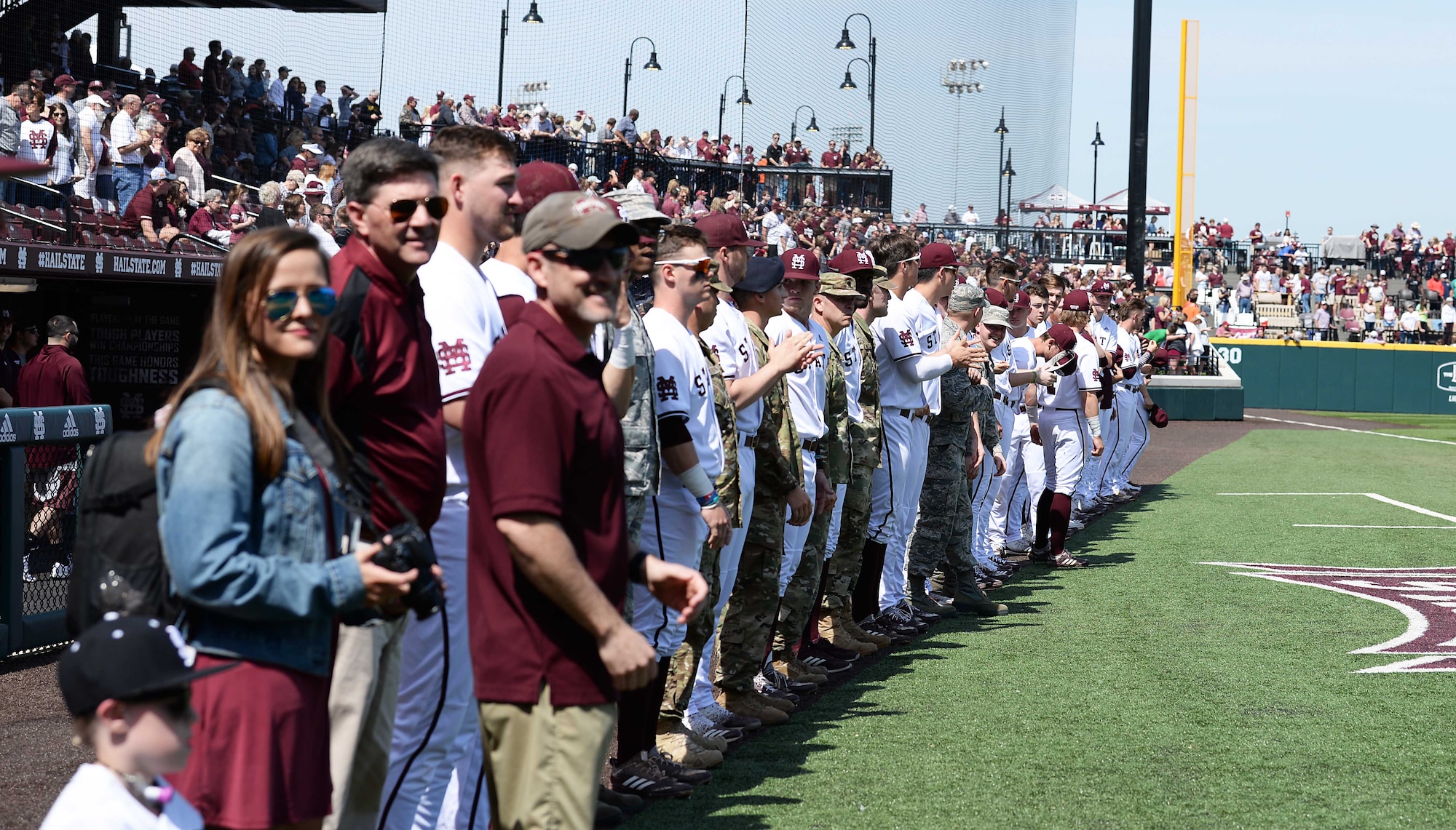 Military personnel stand with the Mississippi State University Bulldogs during a military appreciation baseball game at Dudy Noble Field March 23, 2019, in Starkville, Mississippi. MSU gave recognition to military members with a special “Salute to Service” performance before the game. (U.S. Air Force photo by Airman Hannah Bean)