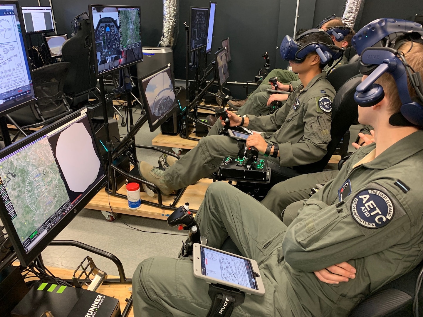 Royal Air Force Flight Officer Syd Janota (foreground), Pilot Training Next 2.0 student, observes a fellow student flying a virtual-reality training sortie at the PTN facility at the Armed Forces Reserve Center in Austin, Texas, March 18, 2019. The RAF have both a student-pilot and an instructor pilot participating in the class as they look to introduce PTN lessons learned into their flying training pipeline.