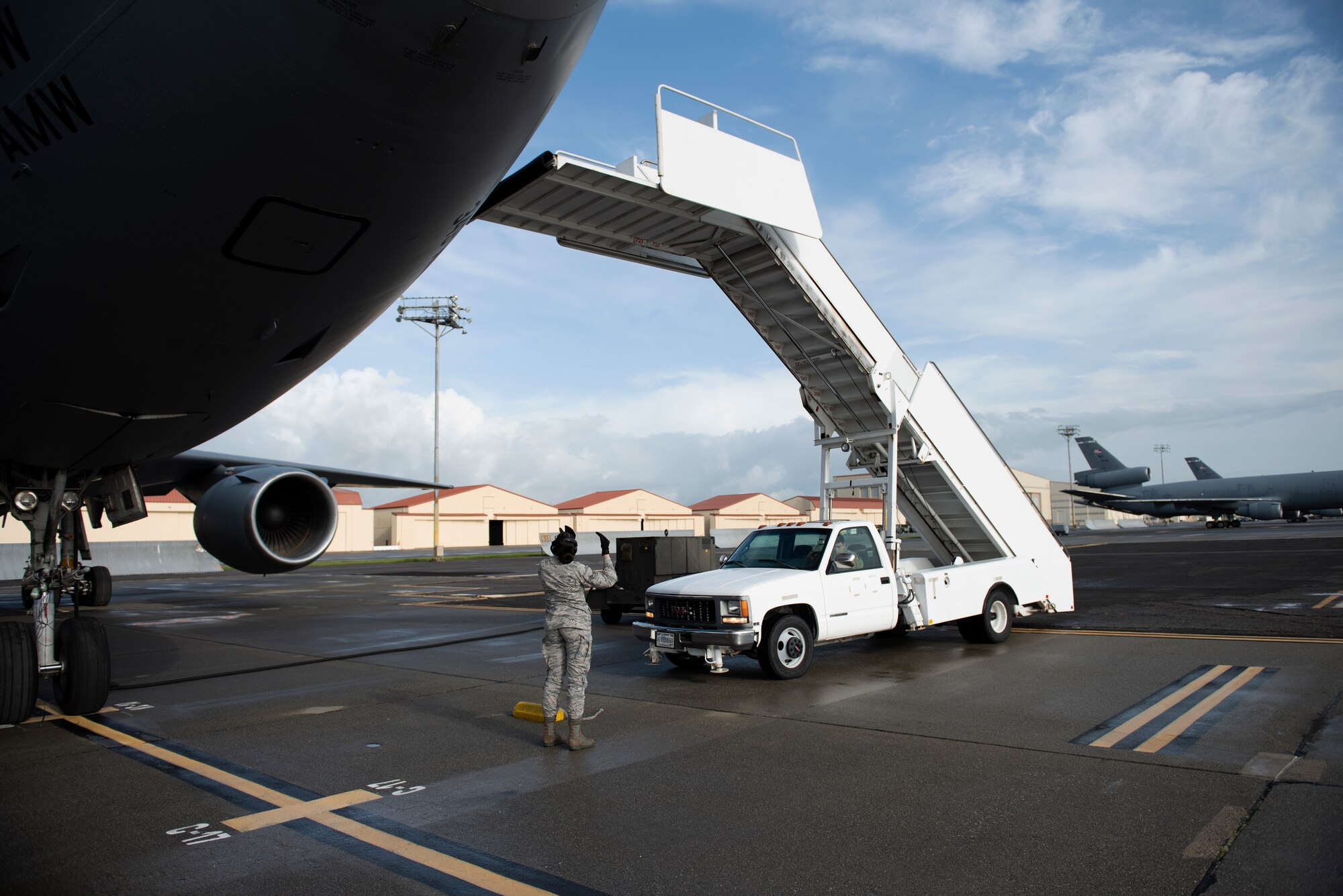 Senior Airman Kayleen Fringle, 60th Aerial Port Squadron passenger services agent, directs a staircase truck into position outside a KC-10 Extender March 28, 2019 at Travis Air Force Base, California. The staircase was used by passengers to enter and exit the aircraft. The KC-10, which flew a refueling mission in support of a Boeing E-3 Sentry and the A-10 Thunderbolt II, will be featured at the Thunder Over the Bay Air Show at Travis March 30-31. (U.S. Air Force photo by Tech. Sgt. James Hodgman)