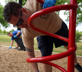 Petty Officer 2nd Class Noe Lopez, assigned to Navy Medicine Education, Training and Logistics Command at Joint Base San Antonio-Fort Sam Houston, disinfects parts of playground during a community relations event held at Martinez Park during a Sailor 360 event.