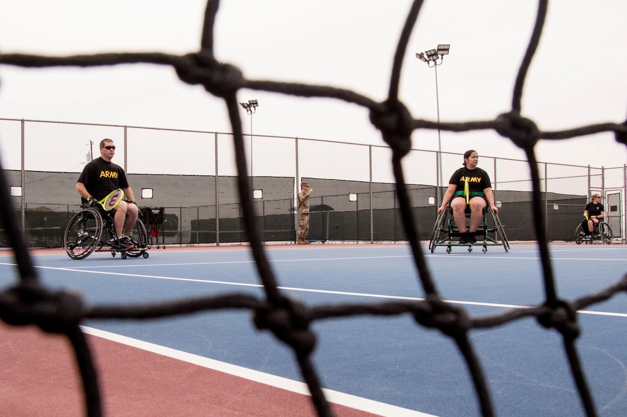 Wheelchair athletes play tennis.