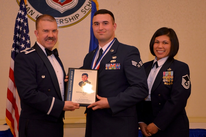 Col. Patrick Winstead, 437th Vice Wing commander, left, and Master Sgt. Calantha Pickel, Airman Leadership School commandant, right, present Senior Airman Cory Germanoff a plaque for earning the John L. Levitow Award during the Airman Leadership School Graduation ceremony March 28, 2019, at the Charleston Club here.