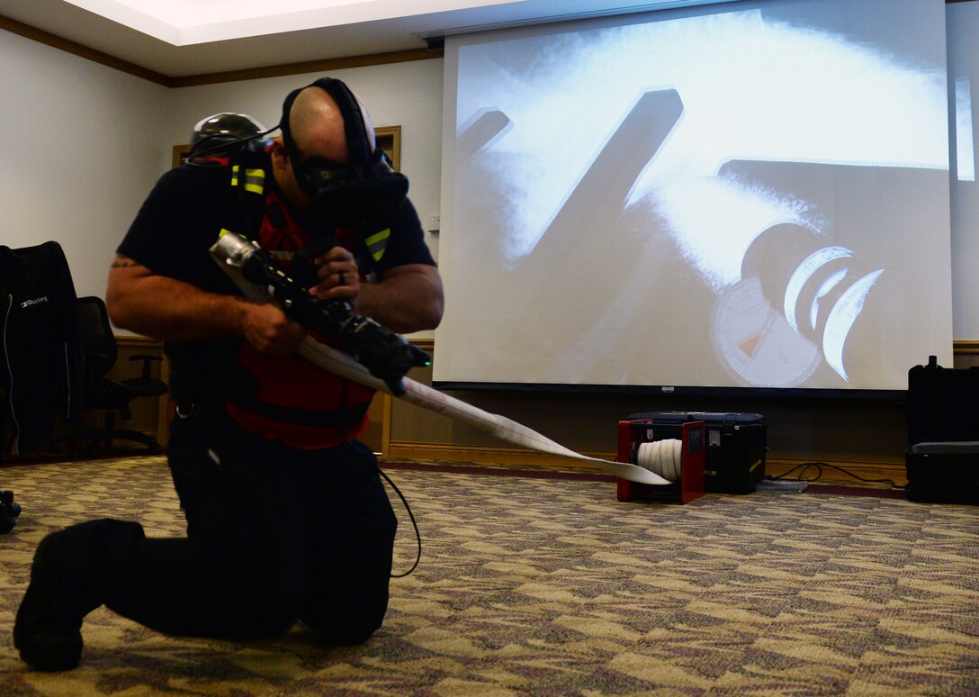 Jeremy Genier, 55th Civil Engineer Squadron firefigher, simulates spraying water on a house fire March 8, 2019, on Offutt Air Force Base, Nebraska. The FLAIM trainer is a firefighter simulator that provides real world scenarios to enhance their skills without being in an unsafe environment. (U.S. Air Force photo by Charles J. Haymond)