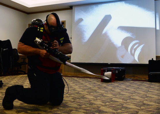 Jeremy Genier, 55th Civil Engineer Squadron firefigher, simulates spraying water on a house fire March 8, 2019, on Offutt Air Force Base, Nebraska. The FLAIM trainer is a firefighter simulator that provides real world scenarios to enhance their skills without being in an unsafe environment. (U.S. Air Force photo by Charles J. Haymond)