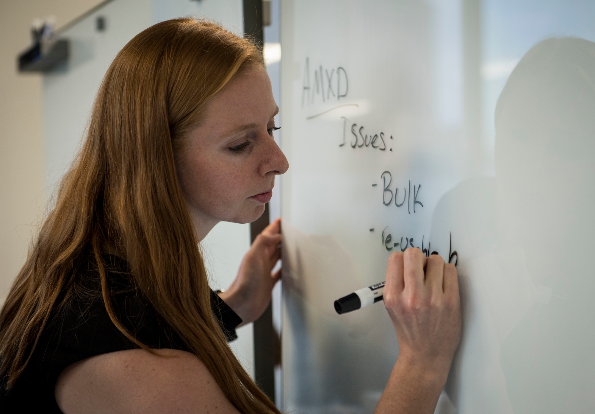 A woman writes on a dry erase board.