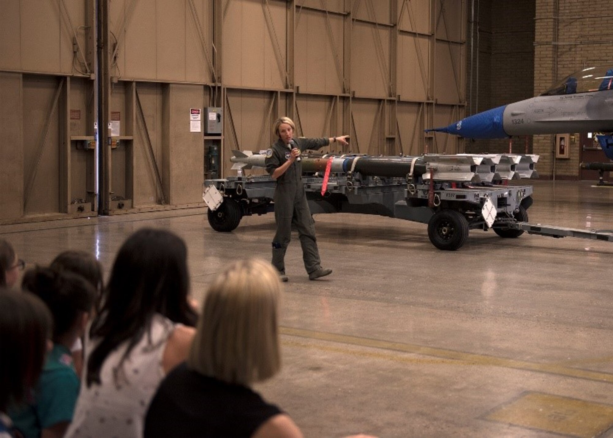 Lt. Col. Kristin Hubbard, 310th Fighter Squadron commander, talks about the capabilities of an F-16 Fighting Falcon to a group of more than a hundred Girl Scouts and their families at Luke Air Force Base, Ariz., March 27, 2019. Hubbard, a pilot with more than 1,600 hours flying F-16 Fighting Falcons, shared her knowledge of the aircraft and what her missions entail. (U.S. Air Force photo by Airman 1st Class Leala Marquez)
