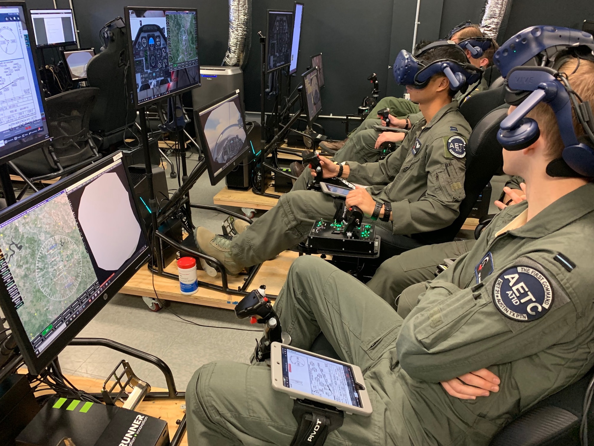 Royal Air Force Flight Officer Syd Janota (fore), Pilot Training Next 2.0 student, observes a fellow student flying a virtual-reality training sortie at the PTN facility at the Armed Forces Reserve Center in Austin, Texas, March 18, 2019. The RAF have both a student-pilot and an instructor pilot participating in the class as they look to introduce PTN lessons learned into their flying training pipeline. (U.S. Air Force photo/Dan Hawkins)